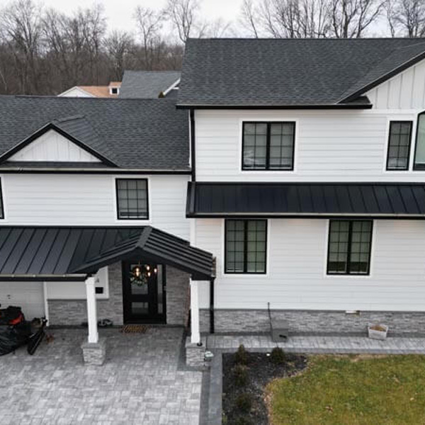 aerial view of home with white siding and dark roof